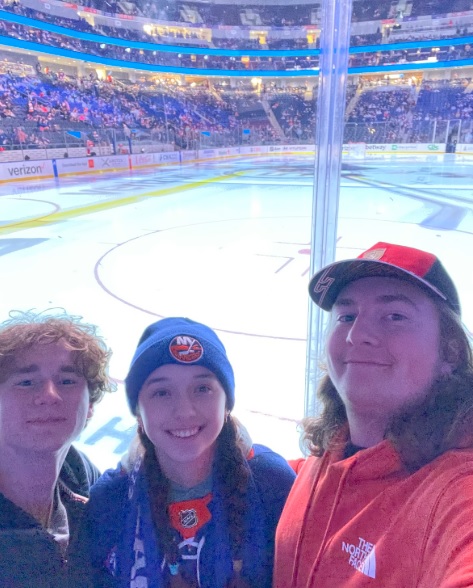 picture of Annelise and two friends at an Islanders game by the rink