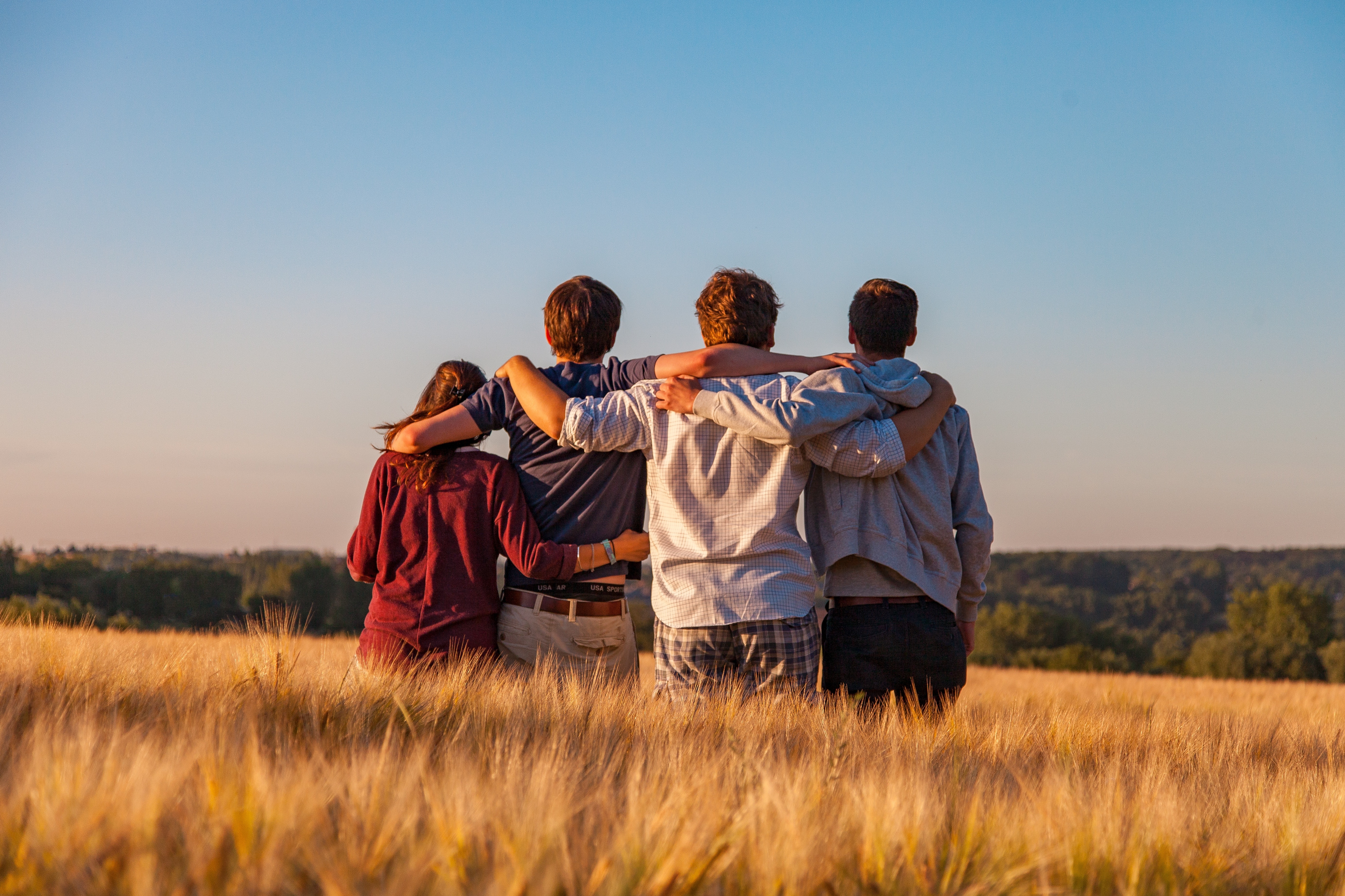 group of friends sitting by a cliff hugging