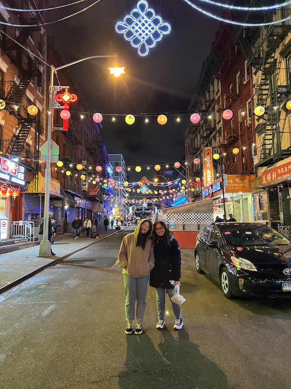 Two girls on the street of Chinatown with Chinese lanterns above.