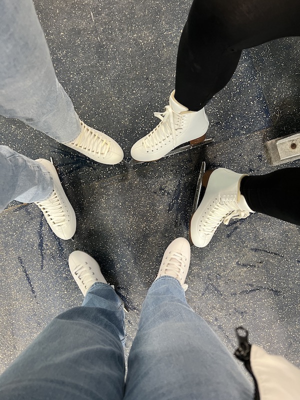 Three pairs of feet with ice skating shoes on.